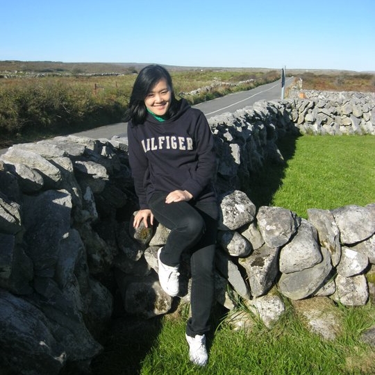 Truong Tuyet sitting on a stone wall in rural Ireland